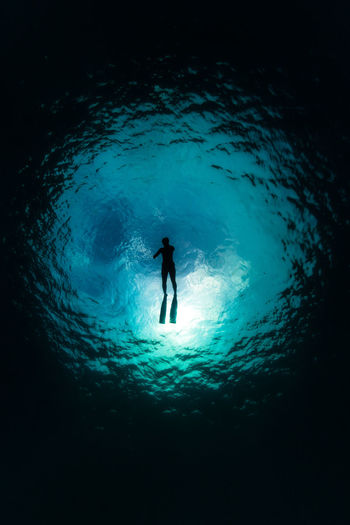 Silhouette person swimming undersea