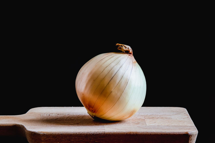 A lone onion on a kitchen wooden board