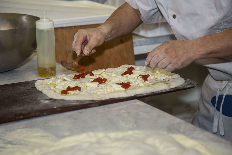 Processing of the pizza dough by the pizza maker.