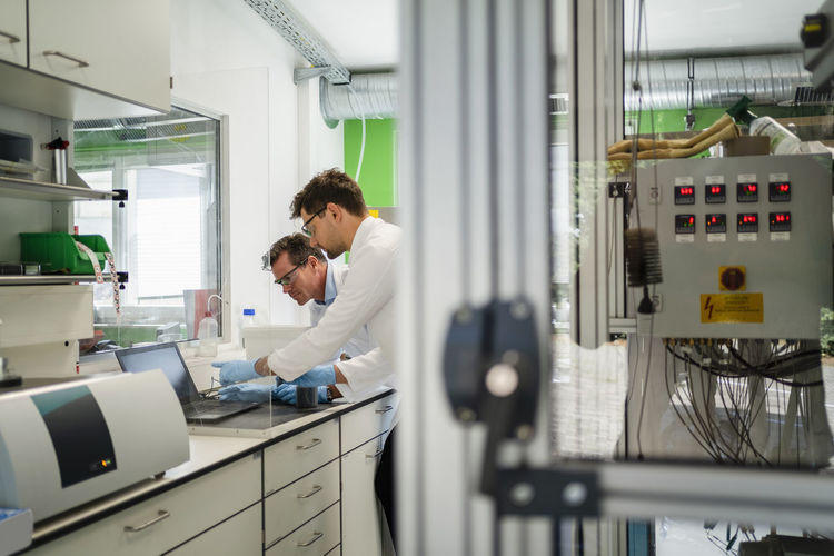 Scientists discussing over laptop in laboratory