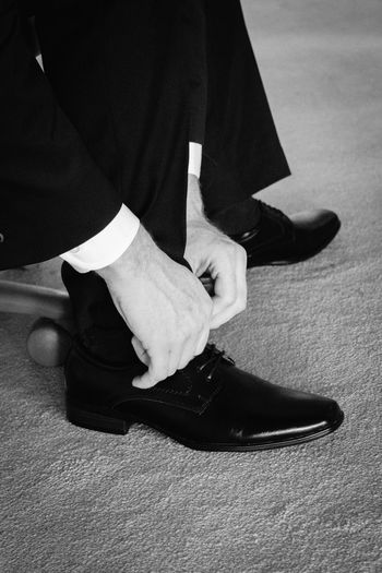 Low section of businessman tying shoelace on floor