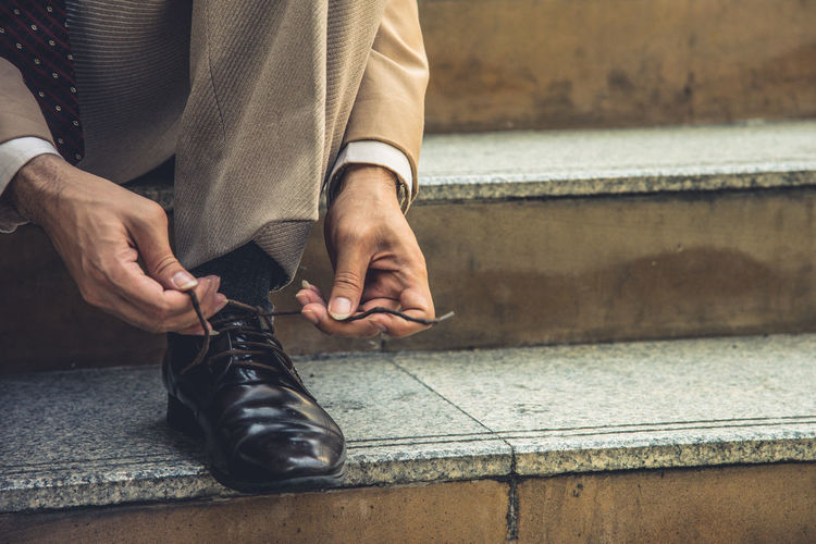 Low section of businessman tying shoelace on steps