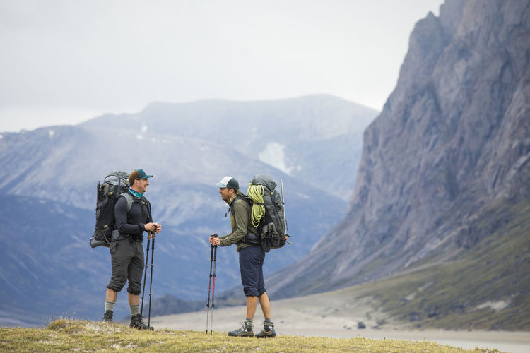 Two friends stop to share a laugh while backpacking in the mountains.