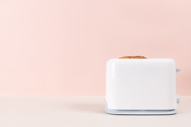 White toaster for toasting bread against pink background. kitchen equipment for fresh morning meal.