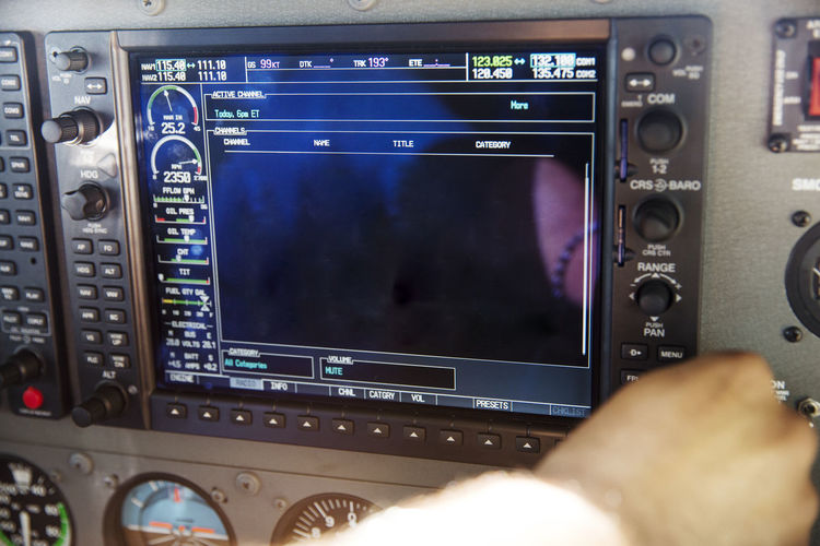 Cropped image of pilot using control panel in airplane cockpit