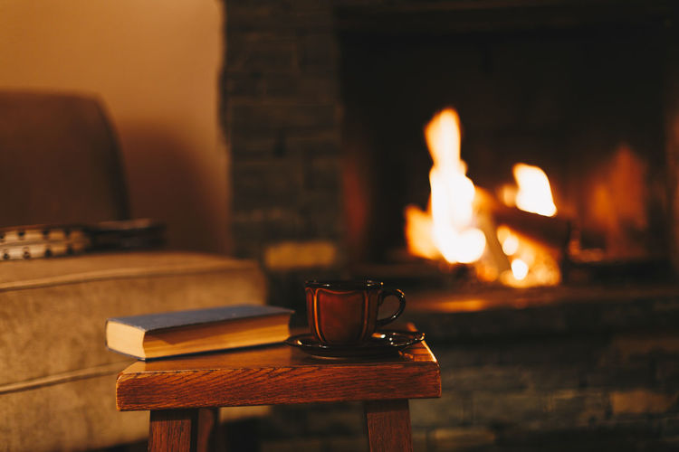 Cosy winter evening in mountain chalet. cup of hot drink in front of fireplace