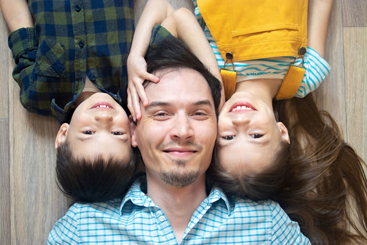 Portrait of smiling father with children lying on floor