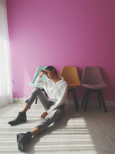 Full length of depressed woman sitting on floor at home