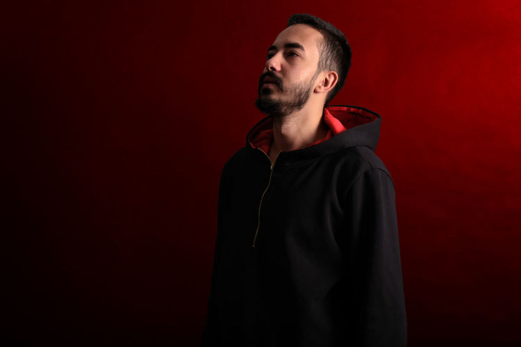 Young man looking away over red background