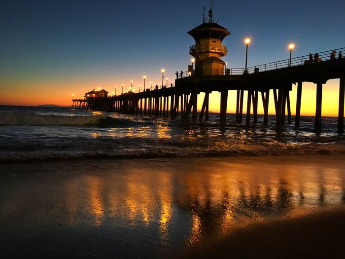 Illuminated huntington beach pier over sea against sky