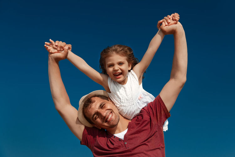 Portrait of smiling father and daughter against sky