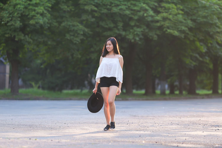Full length portrait of woman on road against trees