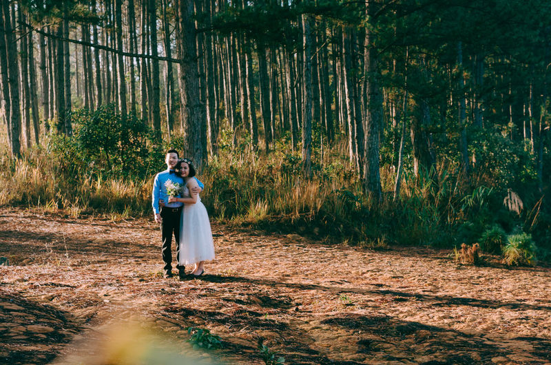 Bride and bridegroom standing in forest
