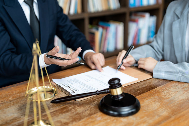 Midsection of lawyer holding gavel on table