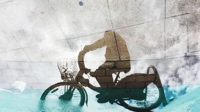 Reflection of person riding bicycle on water