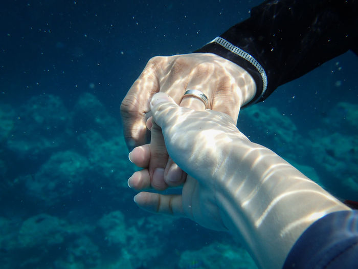Cropped image of couple holding hands undersea