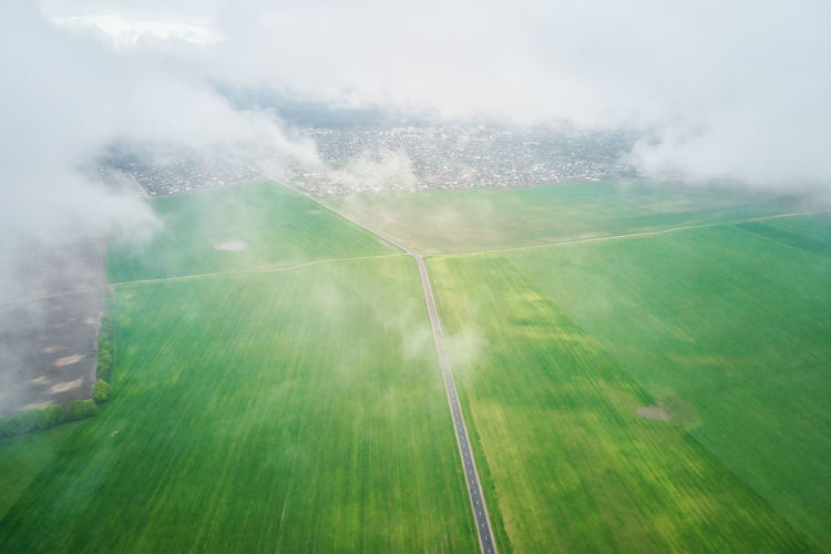 Flight through the clouds. aerial view of green field with fluffy clouds. nature landscape