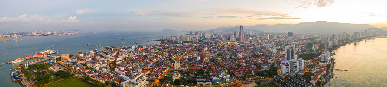 High angle view of city by sea against sky during sunset