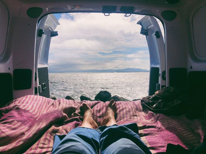 People relaxing by sea against sky