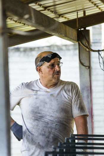 Portrait of a metal worker standing in workshop with dirty shirt.