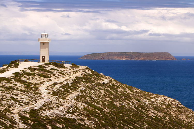 Lighthouse by sea against sky
