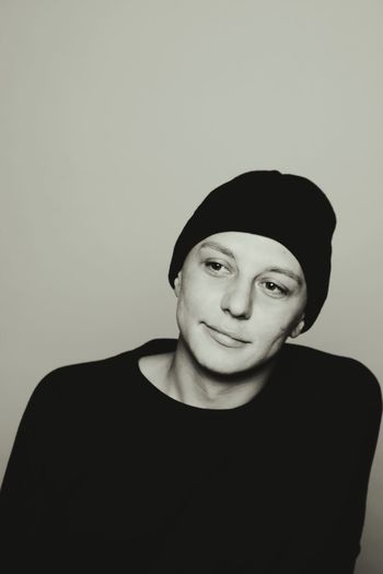 Thoughtful man wearing knit hat against beige background