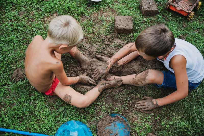 High angle view of sibling playing in mud