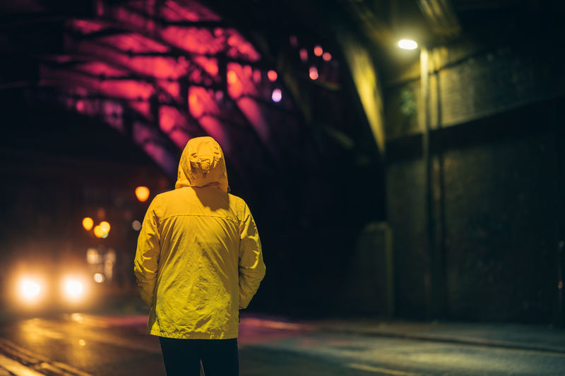 Rear view of man walking on street at night