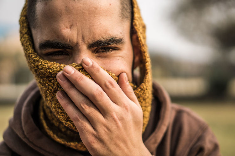 Close-up portrait of man covering face standing outdoors