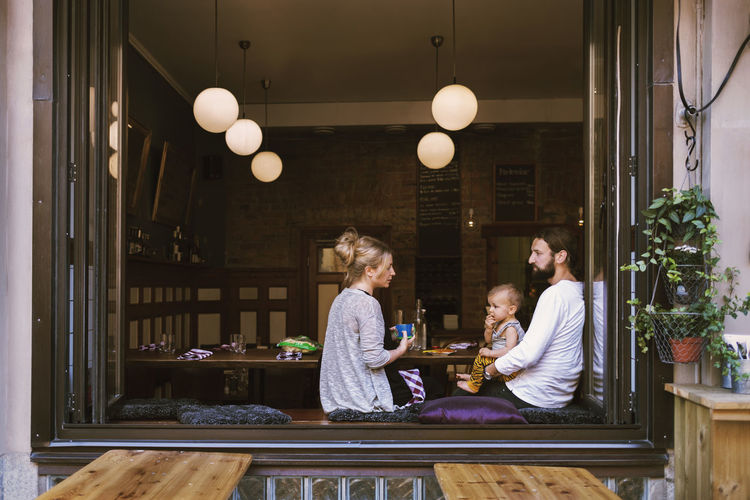 Mid adult parents with son in restaurant seen through window