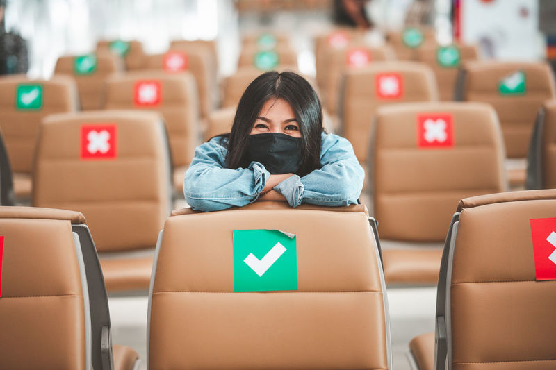 Portrait of woman wearing flu mask sitting at airport