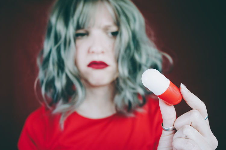 Woman holding capsule against red background