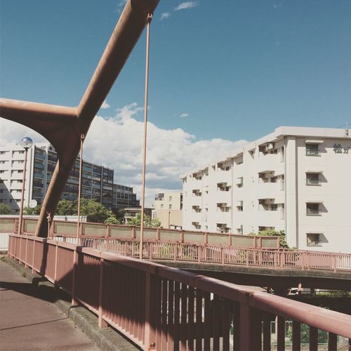 Bridge by buildings against blue sky