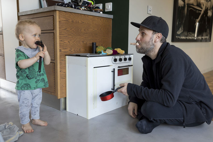 Father and baby son playing with toy kitchen