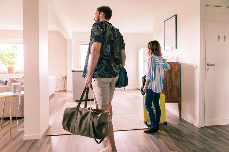 Couple walking with luggage in apartment during staycation