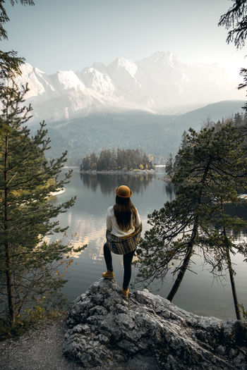 Woman standing on rock while looking at sunrise over mountain