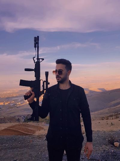 Young man standing on land against sky during sunset