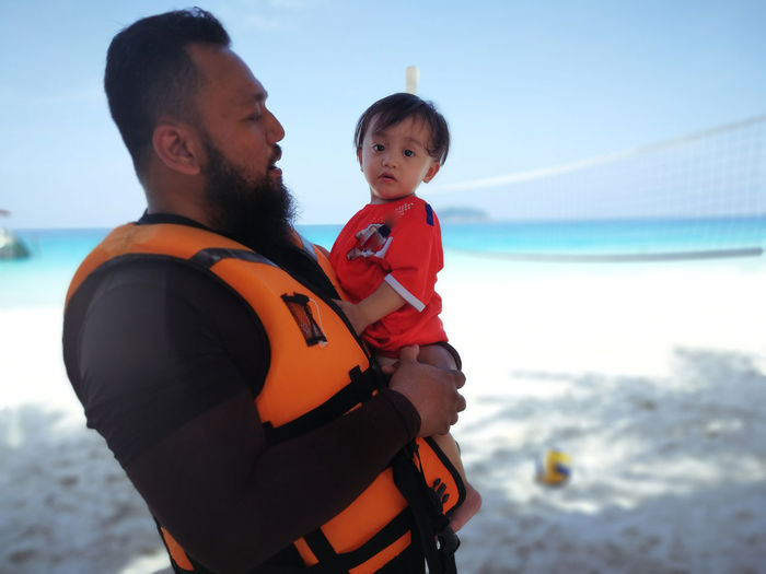 Man carrying baby girl at beach