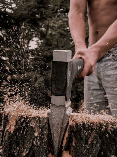 Midsection of man working on wood against trees