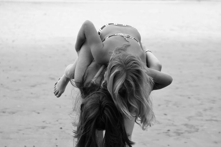 Woman giving daughter piggyback at beach