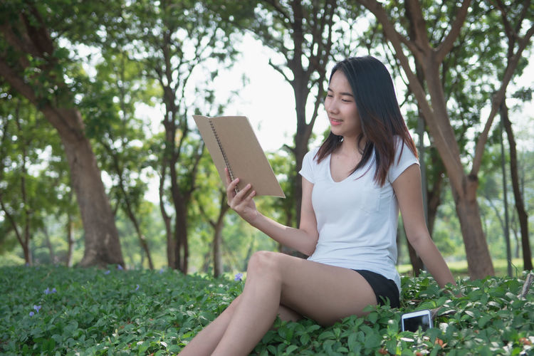 Young woman sitting on mobile phone in park