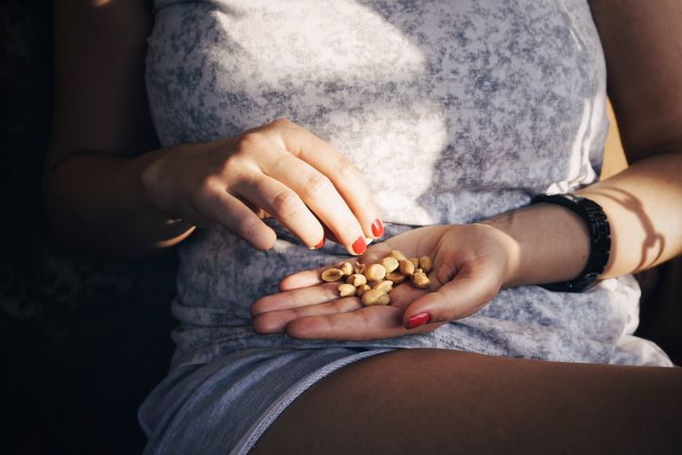 Midsection of woman holding peanuts