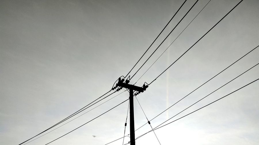 Low angle view of silhouette electricity pylon against sky