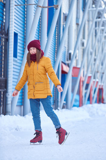 Girl in bright clothes is skating on ice