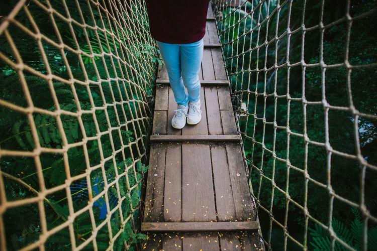 Low section of man standing on footbridge