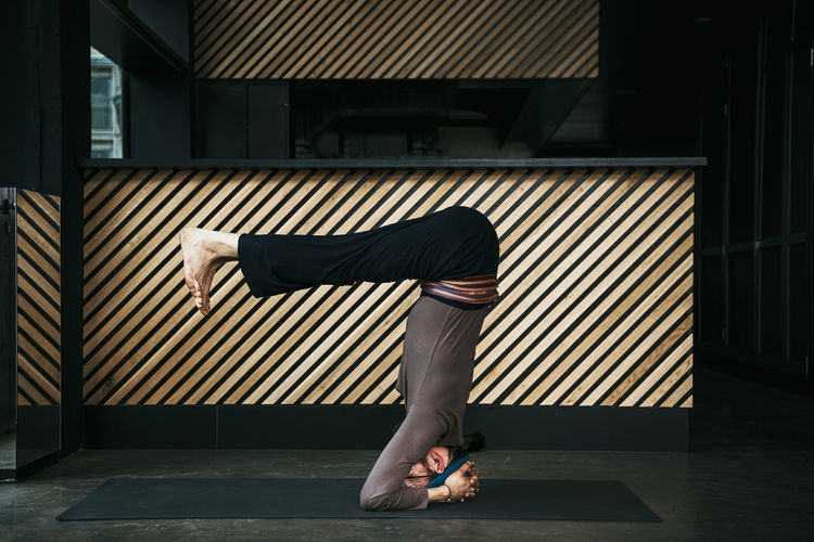 Male yoga instructor doing headstand in exercise room