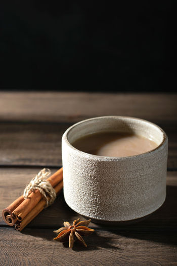 Ceramic cup of masala tea with spice on a wooden table
