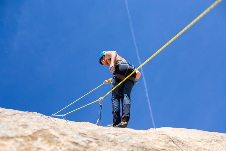 Rear view of shirtless man climbing rock