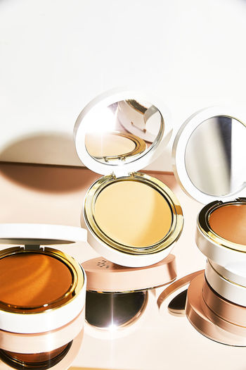 Close-up of 3 colorful makeup compacts