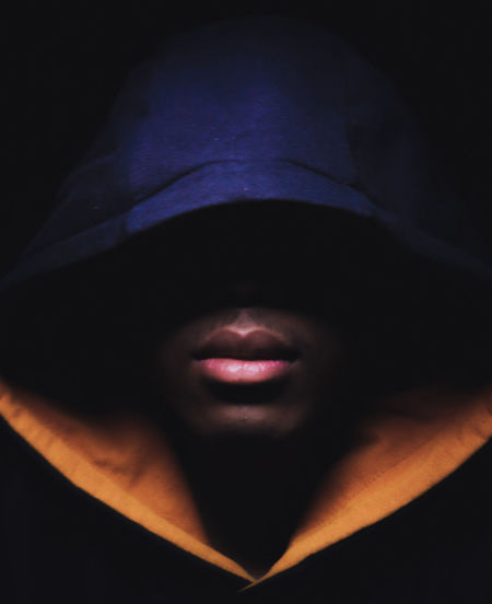 Cropped image of man wearing mask against black background